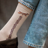 Chaussettes de couleur gris clair au motif mosaïque avec un liseré doré représentant un oiseau. En 85% fil d'écosse, 13% polyamide et 2% élasthanne. Modèle de mi-mollet (courtes) pour femme de la marque Daphné. Fines et légères. Pointures : du 36 au 41